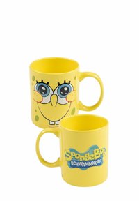 Mug in ceramica gialla con il volto di SpongeBob SquarePants, grandi occhi e un sorriso da un lato; logo "SpongeBob Schwammkopf" dall'altro lato.