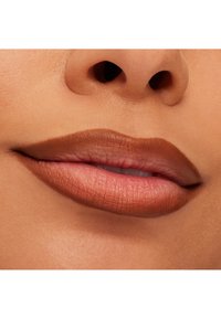 Nærbilde av lepper med en matt brun leppestift. Teksturen er jevn, med definerte kanter, og viser en myk gradient fra mørk til lys.