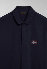 Polo shirt blu navy con tessuto testurizzato, dotato di un'apertura con due bottoni e un piccolo emblema della bandiera islandese sul petto.