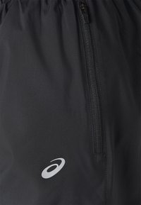 Zwarte sportshorts met een ritszak. Gemaakt van gladde stof, met een klein wit logo near de zoom. Inclusief een elastische tailleband.