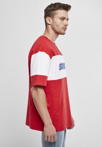 Rood en wit kleur-geblokkeerd t-shirt met korte mouwen, voorzien van een grafische print. Gemaakt van katoen, heeft het een relaxed fit en een ronde hals.