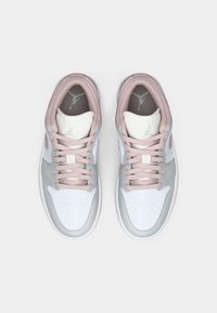 Baskets de sport avec une tige en synthétique et en cuir blanc, des accents gris, des lacets roses et une zone de pointe perforée. Logo sur la languette et sur le côté.