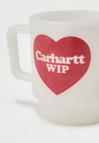 Jäätynyt lasimuki, jossa on valkoinen kahva, ja jossa on punainen sydän sekä valkoinen teksti "Carhartt WIP". Sujuva pinta, sylinterimäinen muoto.