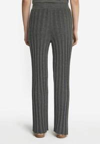 Grå ribstrikkede viddebukser med høj talje, der har lodrette striber og en blød tekstur. Lysebrune sko synlige nederst.