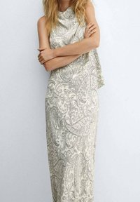 Ærmeløs kjole til anklerne i lys beige med et paisley-mønster i grå. Blødt stof med et flydende design og draperet halsudskæring.