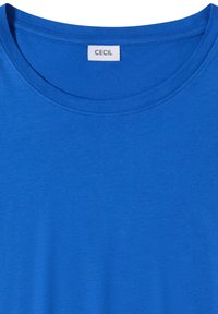 T-shirt bleu vif à col rond avec une étiquette blanche portant l'inscription "CECIL" cousue à l'intérieur du col arrière.