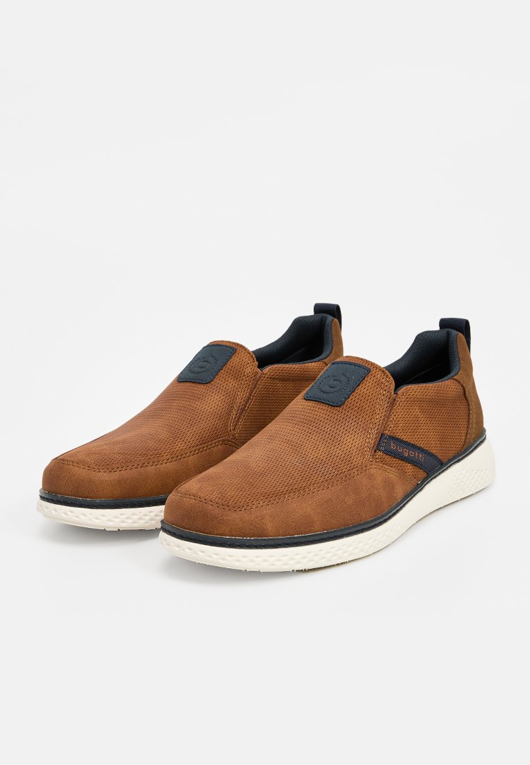 Zapatos marrones tipo slip-on con una parte superior de cuero sintético texturizado, detalles en azul marino y suela de goma blanca con un patrón de relieve visible.