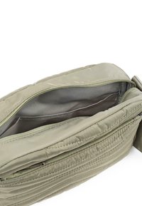 Bolso acolchado de color verde oliva con apertura con cremallera, textura suave y bolsillos interiores. Las características incluyen costuras en contraste y una correa duradera.