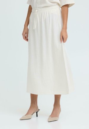 Kvinne iført et hvitt skjørt til knelengde med elastisk midje og snøring, kombinert med beige slingback-sko med spiss tå.