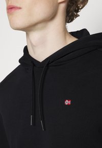 Schwarzer Kapuzenpulli mit Kordelzug, ausgestattet mit einer kleinen gestickten norwegischen Flagge. Glatte Textur, lässiges Design und keine sichtbaren Muster.