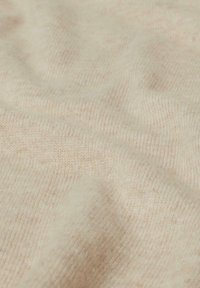 Beige gestrickter Stoff mit einer weichen Textur, der subtile Farbvariationen und ein glattes, warmes Erscheinungsbild aufweist. Keine sichtbaren Muster oder Hardware.