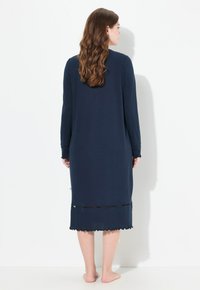 Granatowa sukienka z długim rękawem, okrągłym dekoltem, falbaniastym dołem i koronkowym wykończeniem na dole. Miękka tkanina o luźnym kroju.