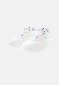 Zapatillas blancas de material sintético, con acentos perforados, cordones planos, suela acolchada y un logotipo en el lateral.