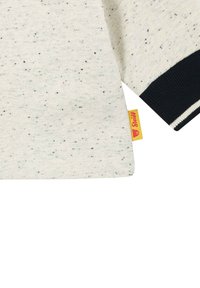 Light gray sweatshirt with dark speckled pattern, contrasting dark ribbed cuffs, and a yellow tag on the seam. Soft, textured fabric.