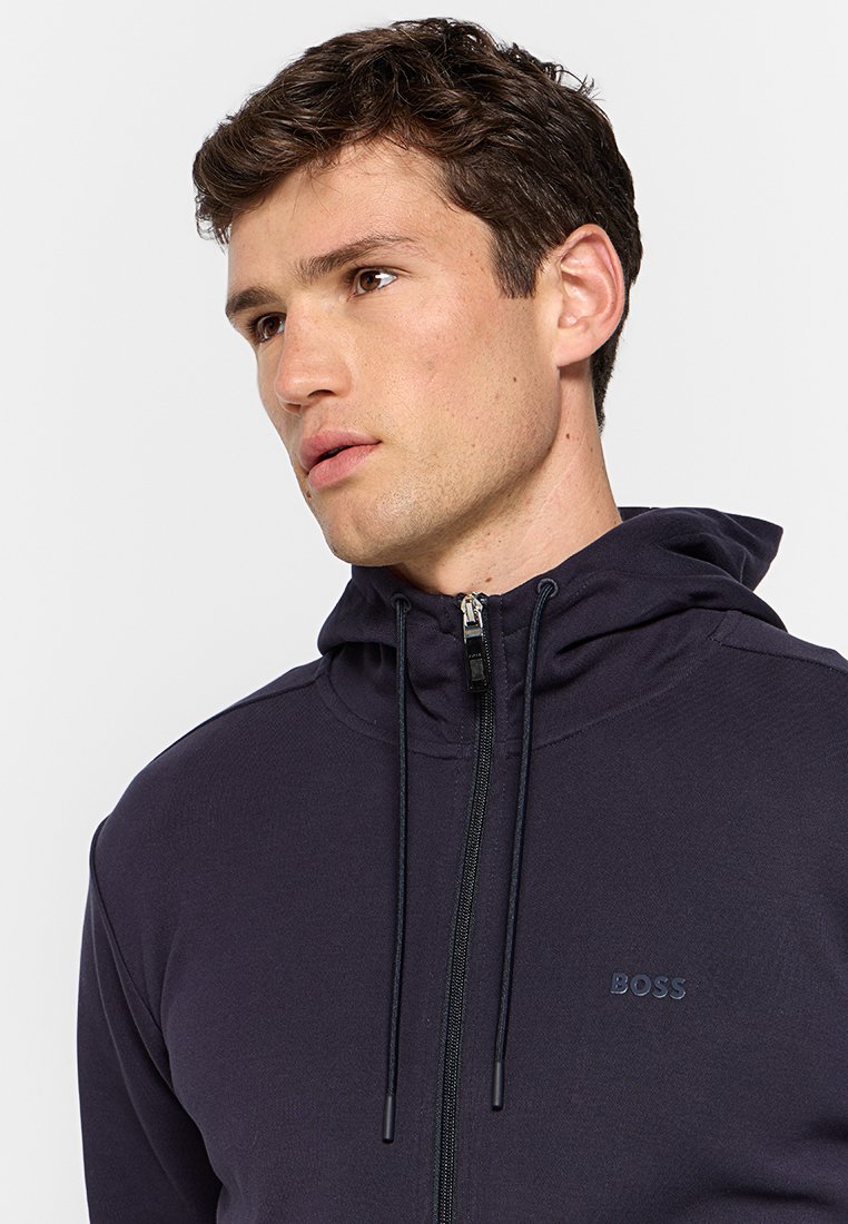 Felpa con cappuccio blu navy con chiusura a zip, dotata di un logo del marchio sul petto, coulisse e una texture liscia.