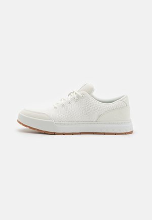 Hvid lavtop sneaker med mesh-overdel, snørelukning, polstret krave og lys brun gummisål på ensfarvet baggrund.
