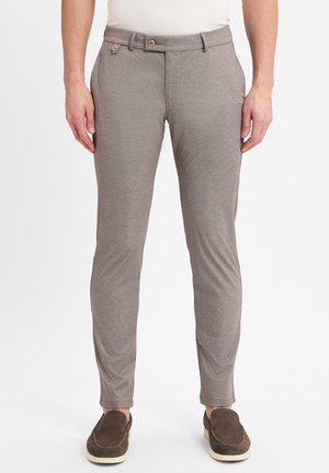Pantaloni grigi, sartoriali, con un tessuto testurizzato, due bottoni frontali e una vestibilità slim. Abbinati a scarpe slip-on marrone scuro.