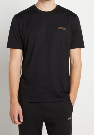 Sort bomulds T-shirt har en rund halsudskæring og korte ærmer. Et diskret brunt logo er broderet på venstre brystområde.