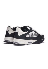 Zapatillas en blanco y negro con parte superior de cuero suave, acentos de malla, cuello acolchado y lettering decorativo en el costado. Suela transparente.