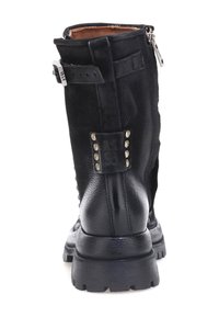 Crna kožna gležnjača s zatvaranjem na patentni zatvarač, teksturiranim završetkom, ukrasnim zakovicama i čvrstim potplatom s jasno definiranim uzorkom.