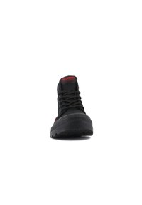 Sneaker nera alta con suola in gomma, parte superiore in tessuto e logo rosso. Presenta lacci e una punta testurizzata per maggiore durata.