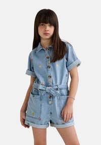 Combishort en denim avec un délavage bleu clair, des manches courtes, un devant à boutons, une taille nouée et une broderie florale multicolore sur les poches et le col.
