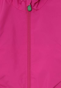 Giacca rosa brillante con una texture liscia e imbottita. Presenta una zip centrale e un toggle verde al collo per le regolazioni.
