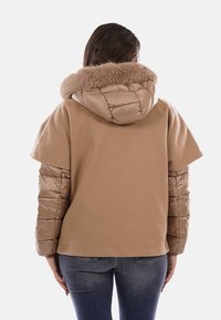 Giacca beige con cappuccio morbido foderato in pelliccia, maniche trapuntate imbottite e design posteriore liscio. Adatta per un abbigliamento casual.