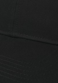 Căciulă neagră cu o textură striată, vizieră structurată și cusături îngrijite. Fabricată dintr-un material cu linii fine și un finisaj neted.