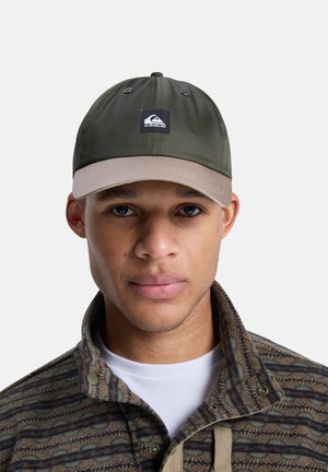 Oliwkowa czapka z daszkiem w beżowym kolorze, z czarną naszywką z logo. Czapka ma otwory wentylacyjne i usztywnioną konstrukcję.