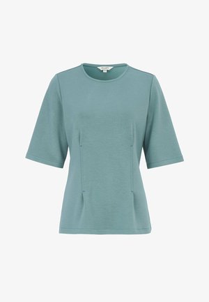 Kortærmet teal top til kvinder med rund halsudskæring og diskrete lodrette sømdetaljer foran, vist på hvid baggrund.