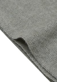 Tissu en tricot gris avec une texture douce, affichant un bord replié qui révèle un tissage fin et une légère peluche.