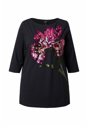 Sort bomuld T-shirt med trekvartærmer med et stort blomsterdesign lavet af flerfarvede pailletter, inklusive pink og grønne accenter.