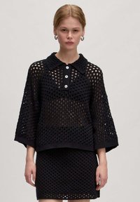 Schwarzes Strickoberteil mit Kragendesign und Knopfleiste; bietet eine lockere Passform und ein offenes Strickmuster, kombiniert mit einem passenden Rock.