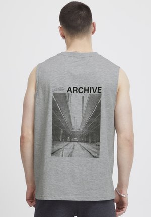 Ärmelloses graues Baumwoll-T-Shirt mit einem großen schwarz-weißen Grafikdruck, der das Wort "ARCHIVE" und den Text darüber zeigt.