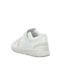 Baskets blanches basses avec col en mesh, semelle épaisse, marque discrète et accent en daim beige au talon.