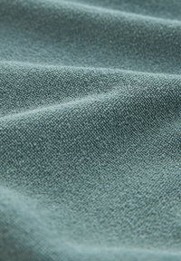 Gros plan sur un tissu bleu clair texturé avec de petites boucles en relief et des plis doux créant des ombres.