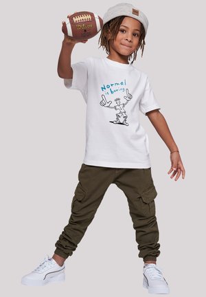 White T-shirt with blue graphic text reading "Normal is boring" and cartoon. Olive cargo pants and white sneakers with gray accents. Holding a football.