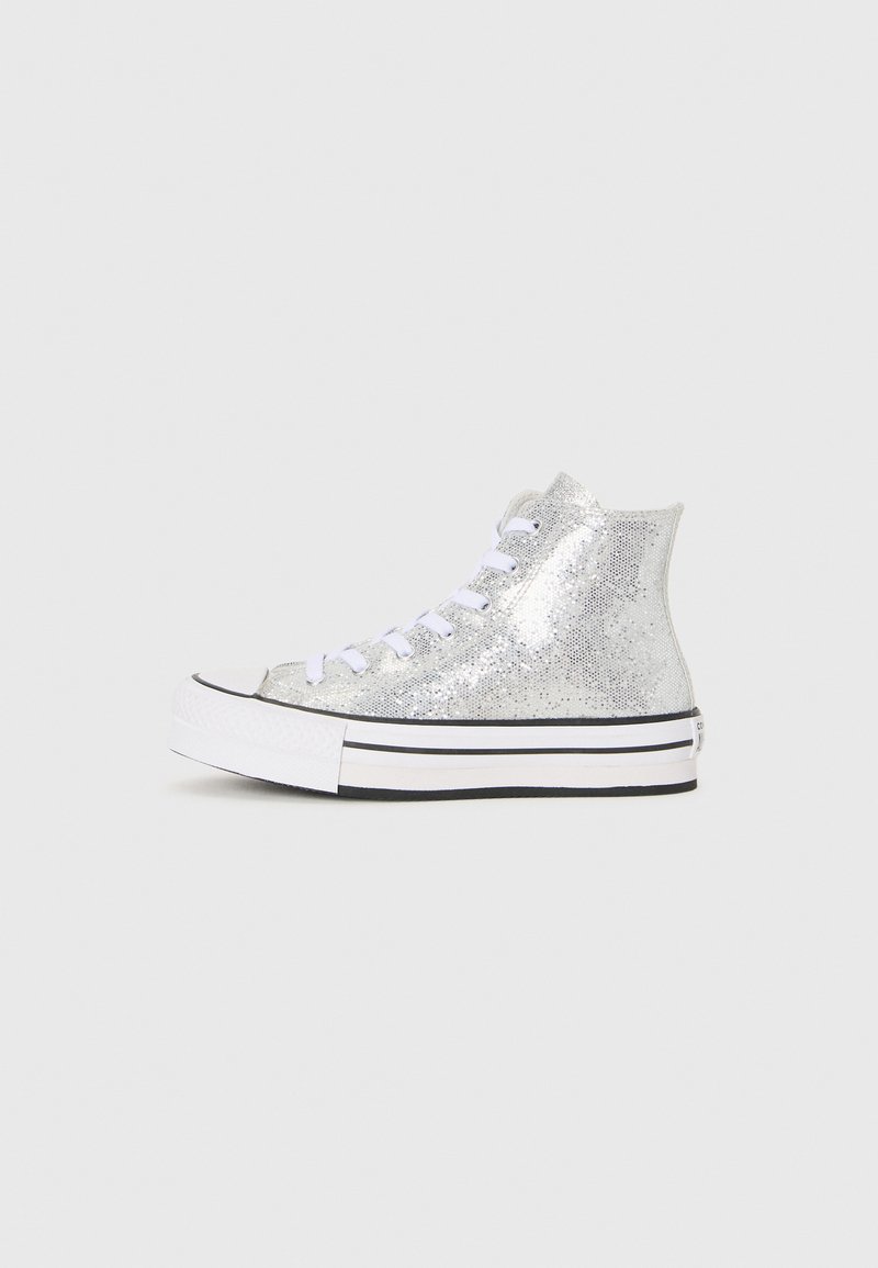 Sneaker alte con una parte superiore argentata luccicante, lacci bianchi e suola in gomma a strisce bianche e nere. Design con punta solida.