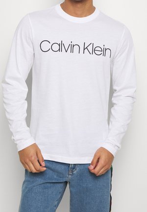 Witte longsleeve t-shirt met het "Calvin Klein" logo in zwart. Klassiek ronde hals ontwerp met geribbelde manchetten en een gladde katoenen textuur.
