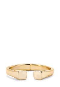 Brazalete abierto en metal dorado pulido, con un diseño minimalista que presenta extremos cuadrados y una textura suave y continua.