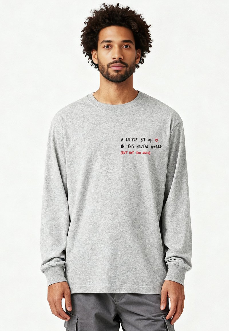 Maglietta grigia a maniche lunghe in cotone, con testo stampato in nero e rosso sul davanti, vestibilità comoda e collo rotondo.
