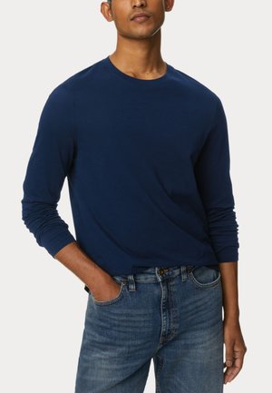 Donkerblauw langemouw t-shirt van zachte stof, met een ronde hals en aansluitende mouwen, gecombineerd met lichtblauwe denim jeans.