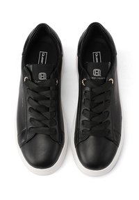 Sneaker nere in pelle con texture liscia, dotate di punta rotonda, lacci neri piatti, suole in gomma bianche e sottili accenti del marchio.