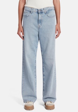 Jeans en denim bleu clair à larges jambes, dotés d'une taille haute, de cinq poches et d'un léger dégradé, associés à des baskets beiges.