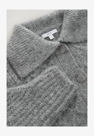 Grauer Strickpullover mit Kragen, ausgestattet mit zwei großen schwarzen Knöpfen und einer strukturierten Oberfläche. Das Markenetikett ist sichtbar.
