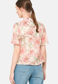 Bluzka w kwiatowy wzór z lekkiej tkaniny, z krótkimi rękawami, w delikatnej pastelowej kolorystyce oraz subtelnym połyskiem dzięki złotym akcentom.