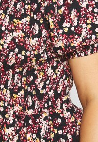 Schwarzes Kleid mit rotem, gelbem und weißem Blumenmuster; gerafftes Oberteil; kurze Puffärmel; strukturierter Stoff; gerafftes Rockdetail.