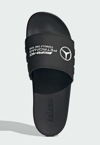 Crne natikače s teksturiranim trakama. Sadrži ispisani bijeli tekst i logo: "AMG PETRONAS FORMULA ONE TEAM" i "adidas" na potplatu.