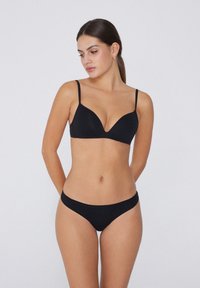 Schwarzes Bikini-Set mit einem Dreiecksbikini-Oberteil mit dünnen Trägern und passenden tief sitzenden Slips, gefertigt aus einem glatten, weichen Stoff.